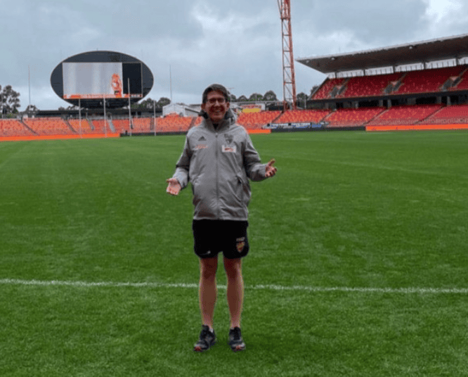 A man standing on footy field.
